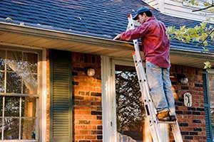 Northern Virginia homeowner cleaning gutters to avoid any roof repairs