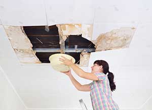 Woman collecting water from a roof leak