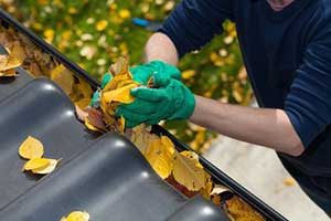 Roofing contractor removing leaves to avoid expensive roof repairs