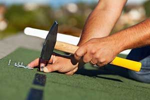 Northern Virginia roofing contractor strategically placing nails in shingle during roof repair