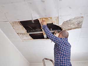 Man collecting water from roof leak