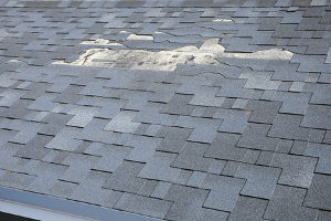 broken shingles warning the homeowner to call a roof repair contractor