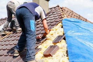 Emergency tarp roofing contractor adding tarp on the top of a roof 