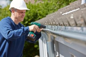 gutter repair contractor in Fairfax, VA wearing a white hard hat and fixing a gutter