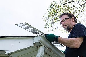 contractor completing a gutter installation while placing gutter guards down so that there is no blockage of leaves or anything else in the way
