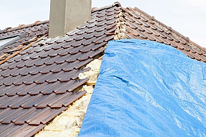 A blue tarp placed on roof by an emergency roof tarping contractor since it's storming and the roof is damaged.
