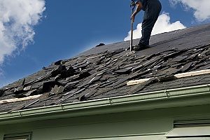 a roof repair contractor removing all the shingles from a roof since minor roof damages contributed to a major roof issue