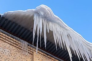 ice dam on top of a roof with icicles forming on the sides of the roof due to the homeowners refusing to contact attic insulation contractors