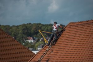 roof repairman repairing roof shingles 