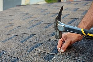 a roof repair contractor based in Fairfax, VA who is performing maintenance on the roof of a house after the owners roof insurance claim became approved
