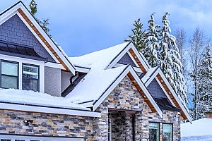a roof of a house that is covered in snow and will need roof maintenance after the winter time since it might cave in over time if not