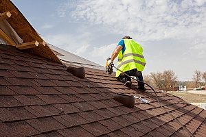 een dakvervangingsaannemer die op een dak werkt in Fairfax, VA dat wordt gedekt door de verzekering van huiseigenaren
