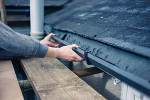 a homeowner checking his gutters while following roof maintenance tips