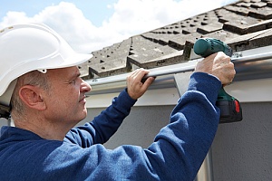 man fixing a roof after determing the roof replacement cost
