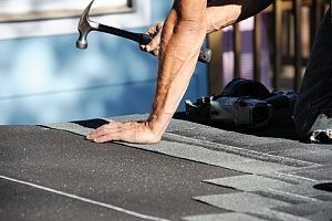 man fixing roof to find out how to price a roof replacement