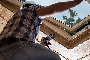 Worker adding caulk insulation to skylight