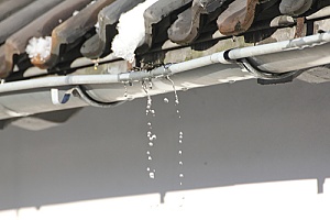 a gutter that has a joint leak and is damaging a home's foundation