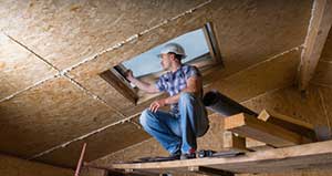 Contractor installing blown-in insulation in an attic ceiling.