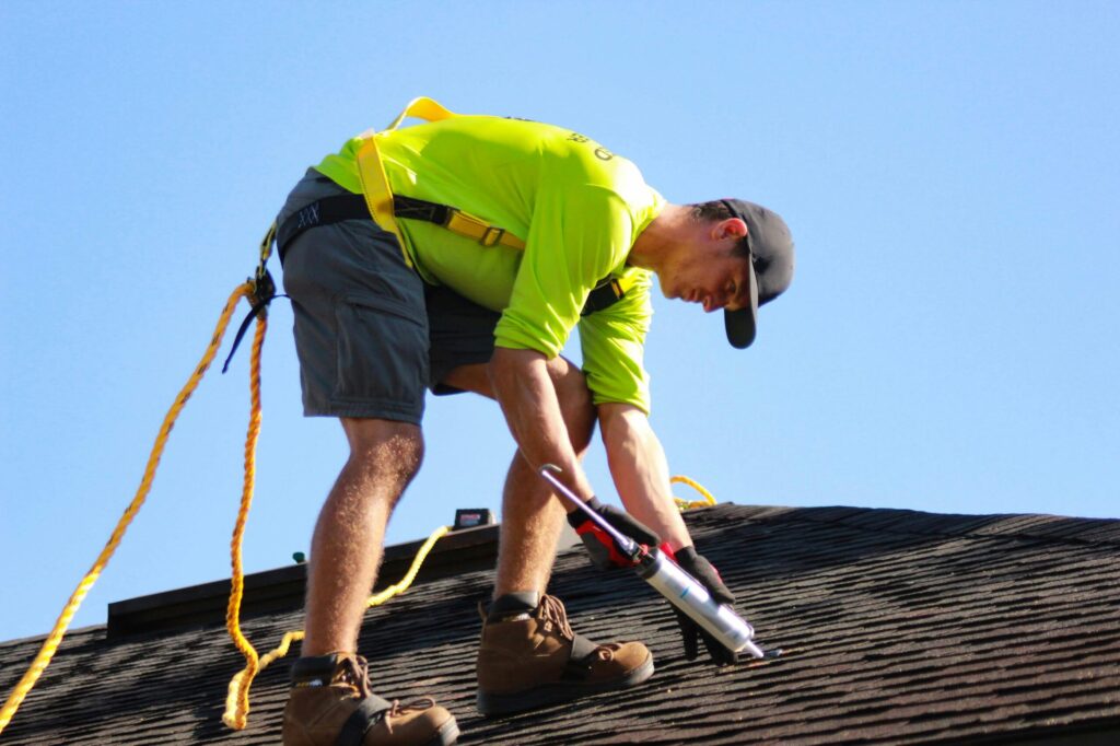 Roofer caulking a roof.