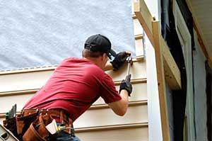 Contractor installing new siding on a house.