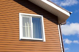 Newly installed orange-brown vinyl siding on a two-story home.