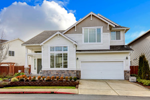 Newly installed white vinyl siding on a two-story home with landscaping and a garage in front. 