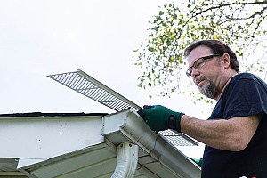 Technician installing plastic gutter guards on a home