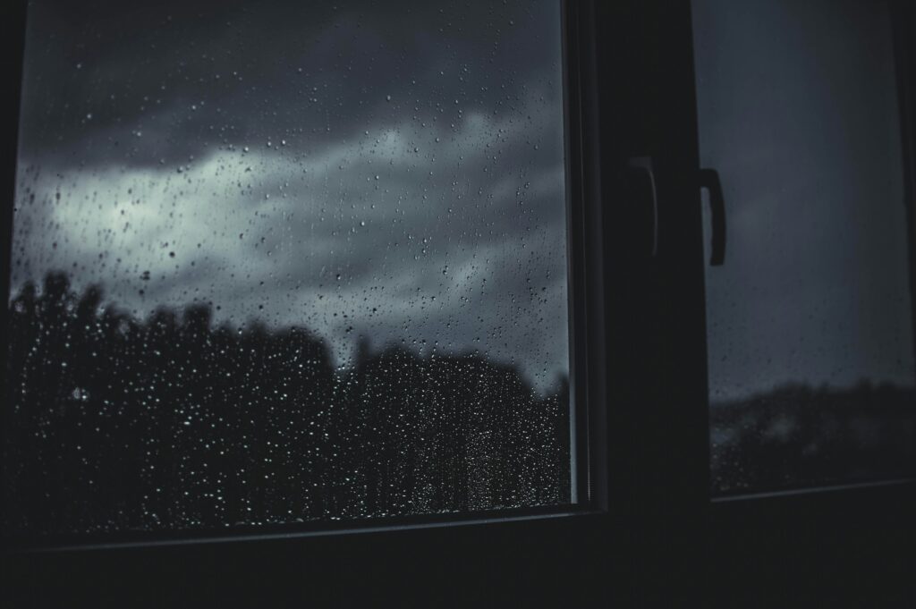 Close view through a window of dark, cloudy skies as a storm approaches.